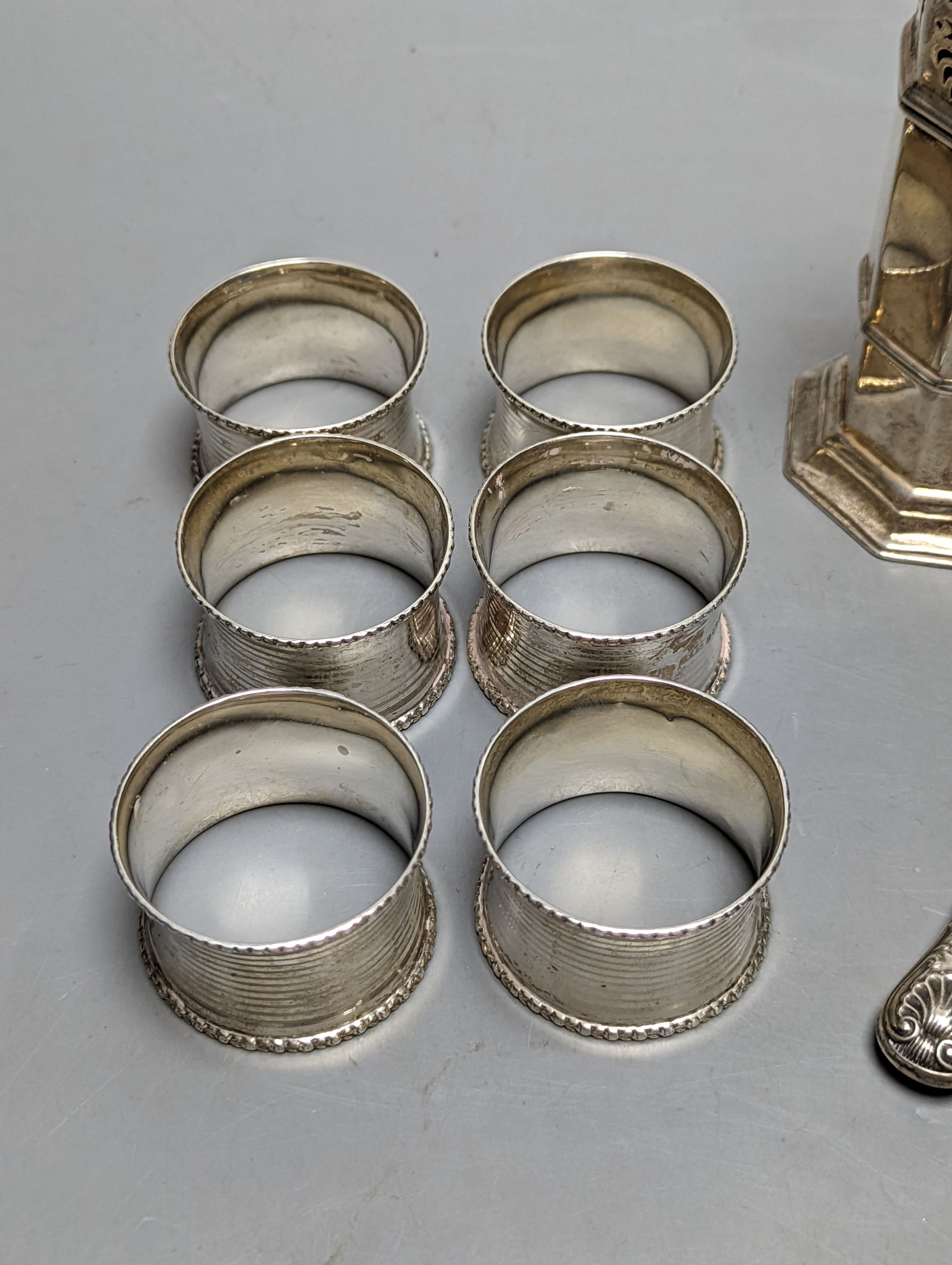 A set of six George V silver napkin rings, Birmingham, 1915, a silver sugar caster and silver butter knife.